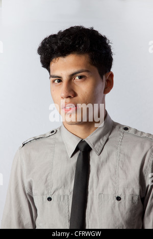 Hübscher junger Hispanic Mann in ein Hemd und dunkle Krawatte, mit einem schockiert oder frustriert oder wütend Blick in die Kamera schaut Stockfoto