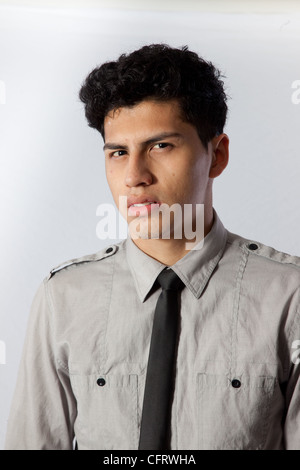 Hübscher junger Hispanic Mann in ein Hemd und dunkle Krawatte, mit einem schockiert oder frustriert oder wütend Blick in die Kamera schaut Stockfoto