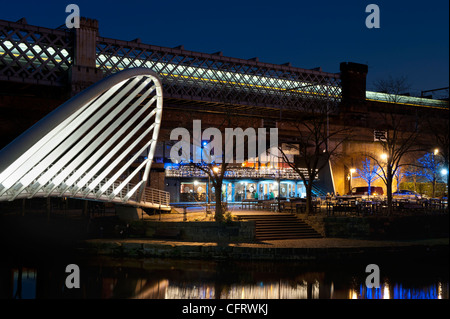 Eine Nachtaufnahme des Kanals im Castlefield, als ein Zug eilt vorbei über eine Brücke im Hintergrund. Stockfoto