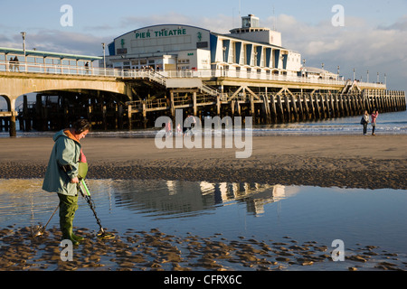 Schatzsuche am Strand von Bournemouth mit Bournemouth Pier im Hintergrund Stockfoto