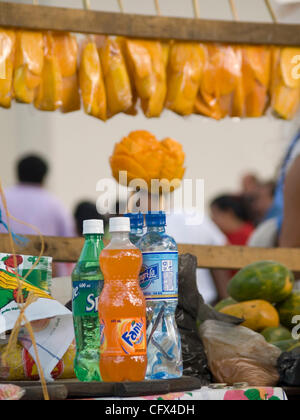 Antigua, Guatemala. 23.03.07 geschnittene frisch Früchte auf Sticks für Verkauf Kontrast mit westlichen alkoholfreie Getränke im Markt Stadt. Stockfoto