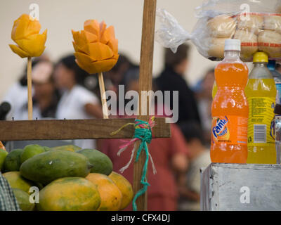 Antigua, Guatemala. 23.03.07 geschnittene frisch Früchte auf Sticks für Verkauf Kontrast mit westlichen alkoholfreie Getränke im Markt Stadt. Stockfoto