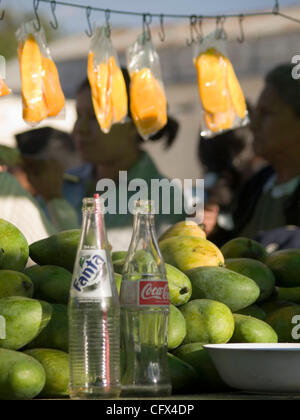 Antigua, Guatemala. 23.03.07 geschnittene frisch Früchte auf Sticks für Verkauf Kontrast mit westlichen alkoholfreie Getränke im Markt Stadt. Stockfoto