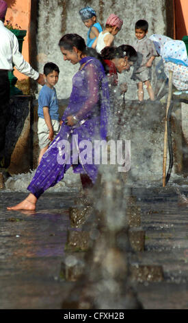 Ein indischer Kasmiri Kind und Frau genießt die Gischt der Brunnen im Nishat Mughal Garten mit Blick auf den berühmten Dal-See in Srinagar, 14. April 2007, während eines Urlaubs markiert das Fest der Baisakhi. Baisakhi, welcher am 14. April gefeiert wird, markiert den Beginn der Erntezeit in Norther Stockfoto