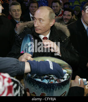 Vladimir Putin mit russischen Kindern an der Eisbahn auf dem Roten Platz in Moscow.Putin brachte ihm eine große Kiste mit Süßigkeiten und Schokolade für Kinder. Stockfoto