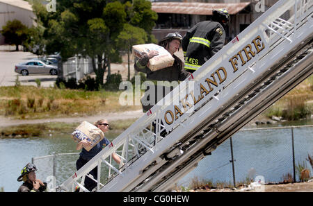 Oakland Feuerwehrleute tragen, Sandsäcke, fallen auf die Ölpest von der Rig, die gegen eine Stadt von Oakland LKW stürzte!-880 in der Nähe von Oak Street Richtung Norden Ausfahrt in Oakland, Kalifornien, auf Freitag, 29. Juni 2007. Das Feuerwehrauto hat am Laney College Parkplatz abstellen schneller Zugang auf das Hochhaus. Stockfoto