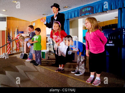 Studenten an einer Fountain Valley, Kalifornien, Grundschule nehmen Sie einen Bogen in Baugruppe nach Unterstützung einen Zauberer (Mitte) führen ein Skit über den Wert der Trennung von verschiedenen Arten von Abfällen (Container im Hintergrund) namens "Recycling--als einfach wie 1-2-3." Stockfoto