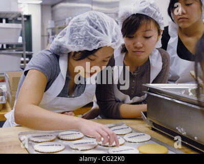 LEDE - Junior Achievement Studenten der Laguna Creek High School, von links, Cheryl Chuong (Cq), Julie Tran (Cq), 16, und Michelle Nguyen (Cq), 16, 17 setzen Logos Cookies & Trüffel Torten, einer örtlichen Bäckerei befindet sich im Inneren der Studentenschaft an CSUS, 12. Februar 2007.  Die Studierenden erhalten praktische exper Stockfoto
