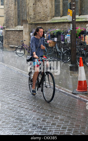 Mädchen-Zyklen, Trinity Street Cambridge UK bei starkem Regen. Stockfoto