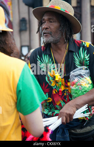 26. August 2012, Sonntag, whistles Nottinghill Carnival, Nottinghill Gate, London, UK - 12,28 H - Mann Verkauf von waren, während des Karnevals in Ladbroke Grove. Bildnachweis: Miguel Sobreira / Alamy Live News Stockfoto