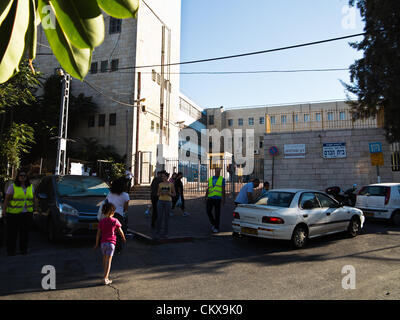 27. August 2012. Eltern tragen helle Westen freiwillig bei der Verkehrsüberwachung und Kursteilnehmer sicheren Zugang auf Bet-Hakerem Grundschule am ersten Tag des laufenden Schuljahres. Jerusalem, Israel. 27. August 2012.   Israelische Kinder gehen wieder zur Schule heute, Abschaffung der traditionellen Sept. 1. Datum, in einer ersten Stufe des Ministeriums für Bildung mit dem Ziel, die Sommerferien 6 Wochen verkürzen eingeleiteten Reformen teilweise entlastet Eltern enorme finanzielle Aufwendungen. Stockfoto