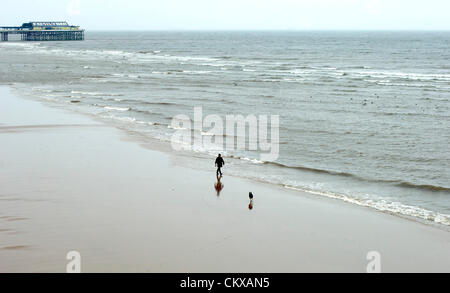 27. August 2012 gehalten nassen und windigen Wetter in Blackpool an den letzten Sommer Feiertag des Jahres die Urlaub Massen entfernt. Ein mutiger Mann mit seinem Hund spazieren leeren Strand in der Anlage. Bildnachweis: Kevin Walsh / Alamy Live News Stockfoto