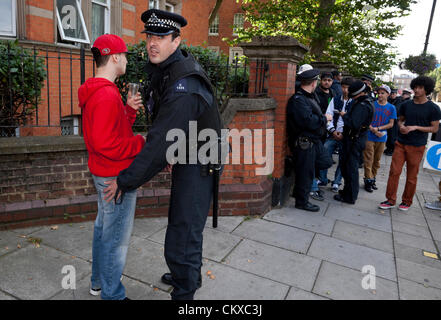 Eine Gruppe von städtischen Polizeibeamten hält an und durchsucht eine Gruppe von Jugendlichen am Notting Hill Carnival. Stockfoto