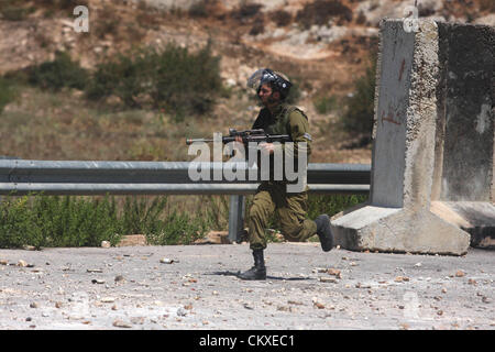 29. August 2012 - Ramallah, Westjordanland, Palästinensische Autonomiegebiete - ein israelischer Soldat hinter palästinensischen Demonstranten außerhalb der Ofer Militärgefängnis läuft, in der Nähe von der Westbank Ramallah am 28. August 2012, während einer Demonstration in Solidarität mit den palästinensischen Häftlinge in israelischen Gefängnissen (Credit-Bild: © Issam Rimawi/APA Images/ZUMAPRESS.com) Stockfoto