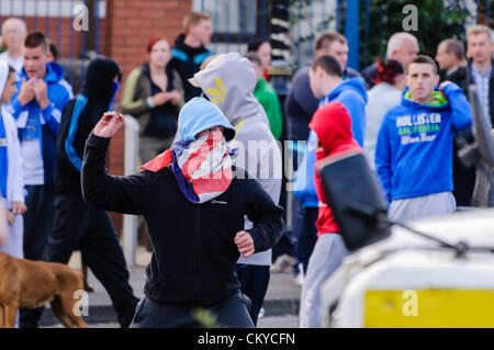 2. September 2012, Belfast - schleudert Jugend mit Union Jack Gesichtsmaske Steinen PSNI Riot Squad. Loyalisten wurden aus Protest gegen eine republikanische Parade in Nordbelfast Gedenken an den Jahrestag des Todes des Henry Joy McCracken verhindert. Stockfoto