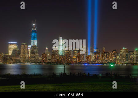 Menschen beobachten und Fotografieren der zwei Lichtstrahlen der Tribute in Light, eine jährliche Erinnerung an die Ereignisse des 11. September 2001, und die Skyline von lower Manhattan vom Liberty State Park in Jersey City, New Jersey.  Dieser Blick auf die Skyline umfasst den Freedom Tower (One World Trade Center). Stockfoto