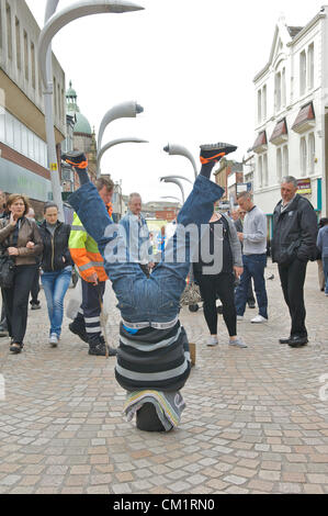 Blackpool, UK. Samstag, 15. September 2012. Blackpool Mann dreht den Kopf nach unten Wirtschaft zu seinem Vorteil.  "Upside down Andy" machen ein Leben steht auf dem Kopf stehend mit dem Kopf in einen Eimer zur Belustigung von Käufern in Blackpool Stadtzentrum entfernt. Stockfoto