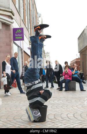 Blackpool, UK. Samstag, 15. September 2012. Blackpool Mann dreht den Kopf nach unten Wirtschaft zu seinem Vorteil.  "Upside down Andy" machen ein Leben steht auf dem Kopf stehend mit dem Kopf in einen Eimer zur Belustigung von Käufern in Blackpool Stadtzentrum entfernt. Stockfoto