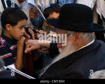 Ein kleiner Junge beobachtet die betenden Stammesältesten in Ehrfurcht vor der Klagemauer, der Kotel, am Vorabend des jüdischen Neujahrs, Rosch ha-Schana. Jerusalem, Israel. 16. September 2012.  Tausenden betet an der Klagemauer am Vorabend des jüdischen Neujahrs zum letzten Mal im Jahr 5772. Nach dem jüdischen Kalender beginnt das Jahr 5773 und die hohen jüdischen Feiertage heute Abend nach Sonnenuntergang. Stockfoto