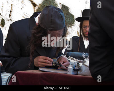 Ein Ultra-orthodoxer religiösen Mann stirbt die Träger seiner Tefilin Gebetsriemen mit schwarzer Tinte an der Klagemauer. Jerusalem, Israel. 16. September 2012.  Tausenden betet an der Klagemauer am Vorabend des jüdischen Neujahrs zum letzten Mal im Jahr 5772. Nach dem jüdischen Kalender beginnt das Jahr 5773 und die hohen jüdischen Feiertage heute Abend nach Sonnenuntergang. Stockfoto