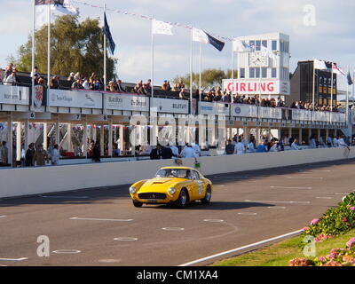 Goodwood Revival Praxis Tag Freitag September 14th.2012. Nr. 60 Ferrari mit einer leuchtend gelben Livree nähert sich der Ziellinie im vorderen Ingenieure und Zuschauer in den Gruben. Stockfoto