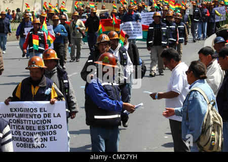 LA PAZ, BOLIVIEN, 18. September 2012. Ein kooperativer Bergmann verteilt der Öffentlichkeit Flugblätter, die ihre Forderungen während eines marsches erklären, um die Regierung zu fordern, Versprechen einzuhalten, ihnen einen größeren Anteil der Konzession an die Mine Colquiri in der Nähe von Oruro zu geben. Kooperative und Angestellte Bergleute, die für das staatliche Bergbauunternehmen COMIBOL arbeiten, streiten seit mehreren Wochen über die Kontrolle der Mine, während die Proteste in der letzten Woche eskalierten. Die Angestellten Bergleute fordern, dass die Mine verstaatlicht wird und die Genossenschaften aufhören, dort zu arbeiten. Stockfoto