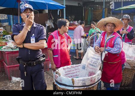 26. September 2012 - Bangkok, Thailand - A-Polizisten und Träger an einer Ecke in Khlong Toey Markt in Bangkok. Khlong Toey (auch genannt Khlong Toei) Markt ist einer der größten '' nass Märkte '' in Thailand. Der Markt befindet sich mitten in einem von Bangkoks größten Slum-Gebieten und in der Nähe von ursprünglichen Tiefwasser-Hafen der Stadt. Tausende von Menschen leben in der benachbarten Slum-Gegend. Tausende Einkaufen mehr in den weitläufigen Markt für frisches Obst und Gemüse sowie Fleisch, Fisch und Geflügel. (Bild Kredit: Jack Kurtz/ZUMAPRESS.com ©) Stockfoto