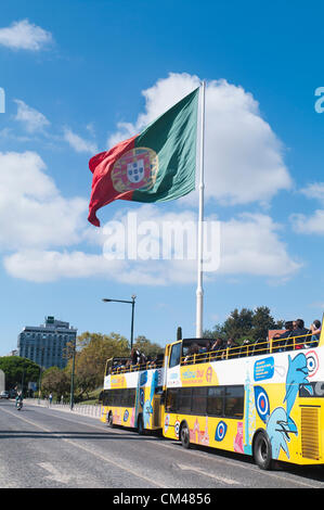 Touristen in einem Sightseeing-Bus in der Nähe des Parks Eduardo VII mit der portugiesischen Nationalflagge, die in Lissabon, Portugal, hoch oben aufsteigt. Stockfoto