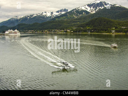 5. Juli 2012 taxis - Borough Of Juneau, Alaska, US - In the Gastineau Channel, Rückkehr nach Juneau, ein Flügel Airways DeHavilland Otter Rundflug Wasserflugzeug nach dem Flug Touristen über die Tongass National Forest und die Gletscher von Juneau Icefield. Auf der rechten Seite ist die â €œCaptain Cook, â € Abenteuer gebunden Alaska 65 ft Trawler, nach der Einnahme von Touristen auf einem Gletscher und Fjord cruise. Auf der linken Seite Regent Seven Seas Navigator, ein Luxus-Kreuzfahrtschiff ist angedockt Juneau seitlich des Kanals gegenüber bergig, bewaldet, Douglas Island. Die Tourismusindustrie ist ein entscheidender Faktor für die Alaskan econ Stockfoto