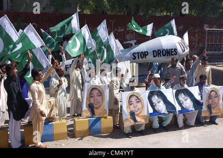 Aktivisten der Bewegung Aafia schreien Parolen gegen Drohnen-Angriffe in Pakistan und für die Freisetzung von Dr. Aafia Siddiqui aus dem US-Gefängnis neben ein riesiges Modell der Drohne Ebene, in Hyderabad.on Freitag, 5. Oktober 2012. Stockfoto