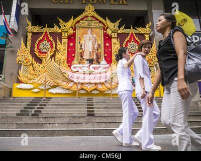 7. Oktober 2012 wird ein Porträt von Bhumibol Adulyadej, der König von Thailand vor dem C.P.-Turm in Bangkok - Bangkok, Thailand - Leute vorbeigehen. Bhumibol Adulyadej ist der amtierende König von Thailand. Er ist bekannt als Rama IX. Er regierte seit 9. Juni 1946, ist er der weltweit am längsten amtierende Staatsoberhaupt aktuelle und der am längsten regierende Monarch in der thailändischen Geschichte. Er wird von den Thais verehrt seinen Geburtstag 5 Dezember ist ein nationaler Feiertag und wird auch in Thailand als Vatertag gefeiert. Wie nähert sich der Geburtstag des Königs, in Aufmachungen Unternehmen riesige Porträts des Königs vor ihrer Bui Stockfoto
