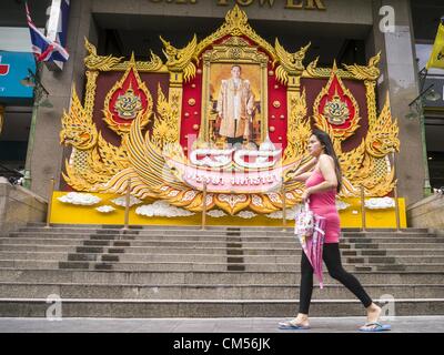 7. Oktober 2012 wird ein Porträt von Bhumibol Adulyadej, der König von Thailand vor dem C.P.-Turm in Bangkok - Bangkok, Thailand - Leute vorbeigehen. Bhumibol Adulyadej ist der amtierende König von Thailand. Er ist bekannt als Rama IX. Er regierte seit 9. Juni 1946, ist er der weltweit am längsten amtierende Staatsoberhaupt aktuelle und der am längsten regierende Monarch in der thailändischen Geschichte. Er wird von den Thais verehrt seinen Geburtstag 5 Dezember ist ein nationaler Feiertag und wird auch in Thailand als Vatertag gefeiert. Wie nähert sich der Geburtstag des Königs, in Aufmachungen Unternehmen riesige Porträts des Königs vor ihrer Bui Stockfoto