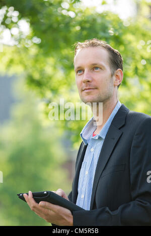 Nachdenklich kaukasischen Jüngling mit digital-Tablette Nachschlagen im freien Stockfoto