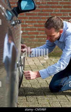 Mitte erwachsener Mann mit Klebeband um zu seinem Auto zu reparieren. Vertikale erschossen. Stockfoto