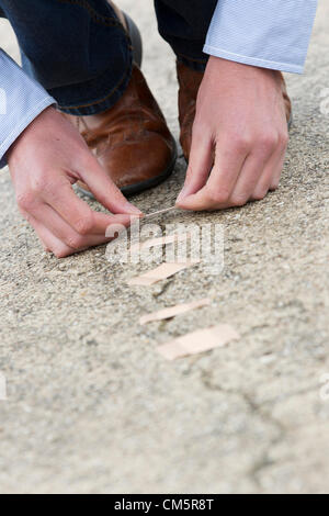 Mannes Hände Anwendung Pflaster über Risse in der Straße. Vertikale erschossen. Stockfoto