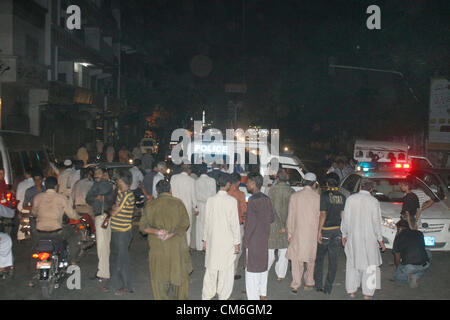 Polizeibeamte und Menschen versammeln sich auf dem Gelände nach einem Brand Vorfall bei Burns Road in Karachi auf Dienstag, 16. Oktober 2012. Stockfoto