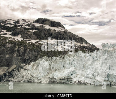 3. Juli 2012 hat - Gletscher-Bucht, Alaska, USA - weit linke Ende des beeindruckenden Margerie Gletscher Schichten von Geröllfelder mit Eis vermischt. Am tiefen Ende der Aqua gefärbtem Wasser der Glacier Bay in Tarr Inlet gelegene Gletscher ist ca. 1 Meile (1,6 km) breit, ungefähr 250 Fuß (76 m) oberhalb des Wasserspiegels und erstreckt sich stromaufwärts 21 Meilen (34 km) bis zu seiner Quelle Mount Root im Bereich Fairweather. Glacier Bay umfasst 3,3 Millionen Hektar (1,3 Millionen) der dynamische Gletscher, gemäßigten Regenwald, schroffe Berge, wilde Küsten, tief geschützten Fjorden und Tierwelt. Ein Highlight der Alaskan einschrauben Stockfoto