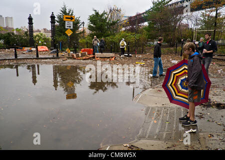 30. Oktober 2012, Brooklyn, NY, USA.  Am Morgen nach dem Hurrikan Sandy New York City, schlug schaut ein Junge mit einem bunten Schirm stehendes Wasser in Plymouth und Main Street in Brooklyn DUMBO Nachbarschaft. Bildnachweis: Joseph Reid / Alamy Live News Stockfoto