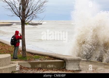 Chicago, Illinois. 30. Oktober 2012. Eine große Welle stürzt in der Ufermauer in der Nähe von North Avenue Beach als ein Mann Risiken ein Foto. 60 km/h Windböen von Hurrikan Sandy Reste erzeugt Wellen, einige von mehr als 20 Fuß. Stockfoto