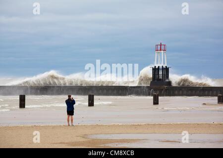 Chicago, Illinois. 30. Oktober 2012.  Ein Mann in kurzen Hosen Fotografien eine große Welle stürzt in der Ufermauer und Navigation Beacon auf Nordstrand Allee. 60 km/h Windböen von Hurrikan Sandy Reste erzeugt Wellen, einige von mehr als 20 Fuß. Stockfoto
