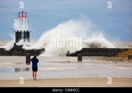 Chicago, Illinois. 30. Oktober 2012.  Ein Mann in kurzen Hosen Fotografien eine große Welle stürzt in der Ufermauer und Navigation Beacon auf Nordstrand Allee. 60 km/h Windböen von Hurrikan Sandy Reste erzeugt Wellen, einige von mehr als 20 Fuß. Stockfoto