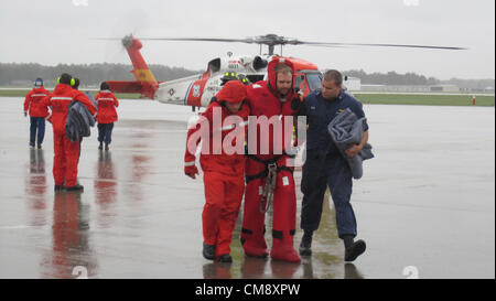 Bodenpersonal von Coast Guard Air Station Elizabeth City, North Carolina, unterstützen einen Segler aus der Großsegler Bounty aus einem MH-60 Jayhawk Helikopter auf einem Kleiderbügel in die Air Station Montag, 29. Oktober 2012. Zwei Jayhawk Besatzungen gehisst 14 Überlebenden aus der Fülle, nachdem die Überlebenden das Schiff verlassen, als es anfing, unter Wasser 90 Meilen südöstlich von Cape Hatteras, North Carolina, während Hurrikan Sandy. Foto: U.S. Coast Guard Lt. Zach Huff/Archiv Bild Stockfoto