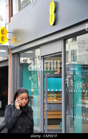 Oxford Street, London, UK. 31. Oktober 2012. Eine Frau auf einem Mobiltelefon geht vorbei an der Re-Branding EE-Store auf der Oxford Street. EE (Everything Everywhere) startet 4G superschnellen Breitband in ganz Großbritannien. Zunächst in London, Leeds, Liverpool, Manchester, Sheffield, Glasgow, Edinburgh, Cardiff, Bristol, Birmingham und Southampton erhältlich. Stockfoto