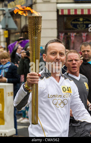 Northampton UK. 2. Juli 2012. Andy Wightman trägt die Olympische Fackel nach unten St Giles Street vor dem Guildhall Northampton Town Center, genauso wie der Regen beginnt. Stockfoto