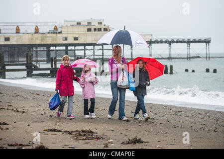 Aberystwyth, Wales, UK. Freitag, 6. Juli 2012 The CHAMPION Familie von Oswestry Shropshire, auf ein Wochenende Wohnwagen Urlaub in Aberystwyth, Schutz vor den Schlagregen. Die Environment Agency hat Amber Alerts Warnung vor der Gefahr von Überschwemmungen auf Flüssen in Wales, und einen Monat im Wert von Regen wird vorausgesagt, um in Teilen des Vereinigten Königreichs an nur einem Tag fallen.  Foto © Keith Morris Stockfoto