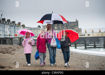 Aberystwyth, Wales, UK. Freitag, 6. Juli 2012 The CHAMPION Familie von Oswestry Shropshire, auf ein Wochenende Wohnwagen Urlaub in Aberystwyth, Schutz vor den Schlagregen. Die Environment Agency hat Amber Alerts Warnung vor der Gefahr von Überschwemmungen auf Flüssen in Wales, und einen Monat im Wert von Regen wird vorausgesagt, um in Teilen des Vereinigten Königreichs an nur einem Tag fallen.  Foto © Keith Morris Stockfoto