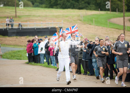 6. Juli 2012, Hadleigh, Essex, England. Die Olympische Fackel betritt der Hadleigh Farm Mountain Bike Austragungsort der Olympischen Spiele wo es Dan Jarvis weitergegeben wird der Teil der Route mit dem Mountainbike fahren wird, während die Fackel hält. Die Läufer wurden von einigen 400 Schulkinder und Würdenträger eingeladen zu diesem Anlass begrüßt. Stockfoto