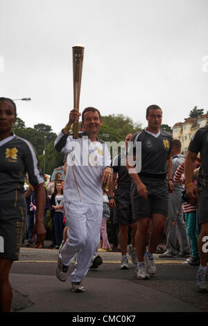 Bournemouth, UK Freitag, 13. Juli 2012. Olympischer Fackellauf in Bournemouth, UK - Läufer Ian Kennedy, Wimborne Leichtathletik Vereinstrainer, nimmt die Fackel in die untere Gärten in Bournemouth am Freitagabend Stockfoto