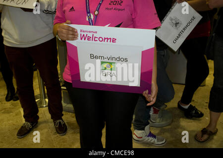 17. Juli 2012.  London Heathrow, Vereinigtes Königreich.  Olympische Konkurrenten und Beamten kommen an Terminals des Flughafens Heathrow. Beamter mit ein Willkommen Zeichen in Portugiesisch für Brasilien-Olympiamannschaft Stockfoto