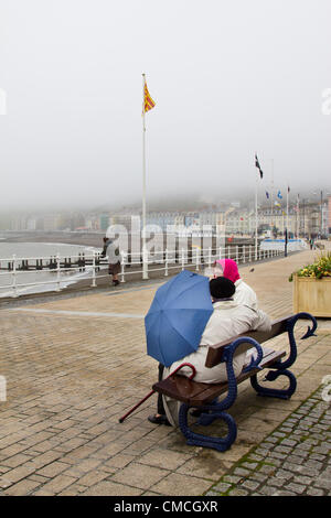 Aberystwyth Promenade in mid Wales Besucher nehmen Schutz vor Regen und Nebel unter einem blauen Dach wie heftige Wetter einen sehr schlechten Start auf die 2012 Saison ankündigt. Stockfoto